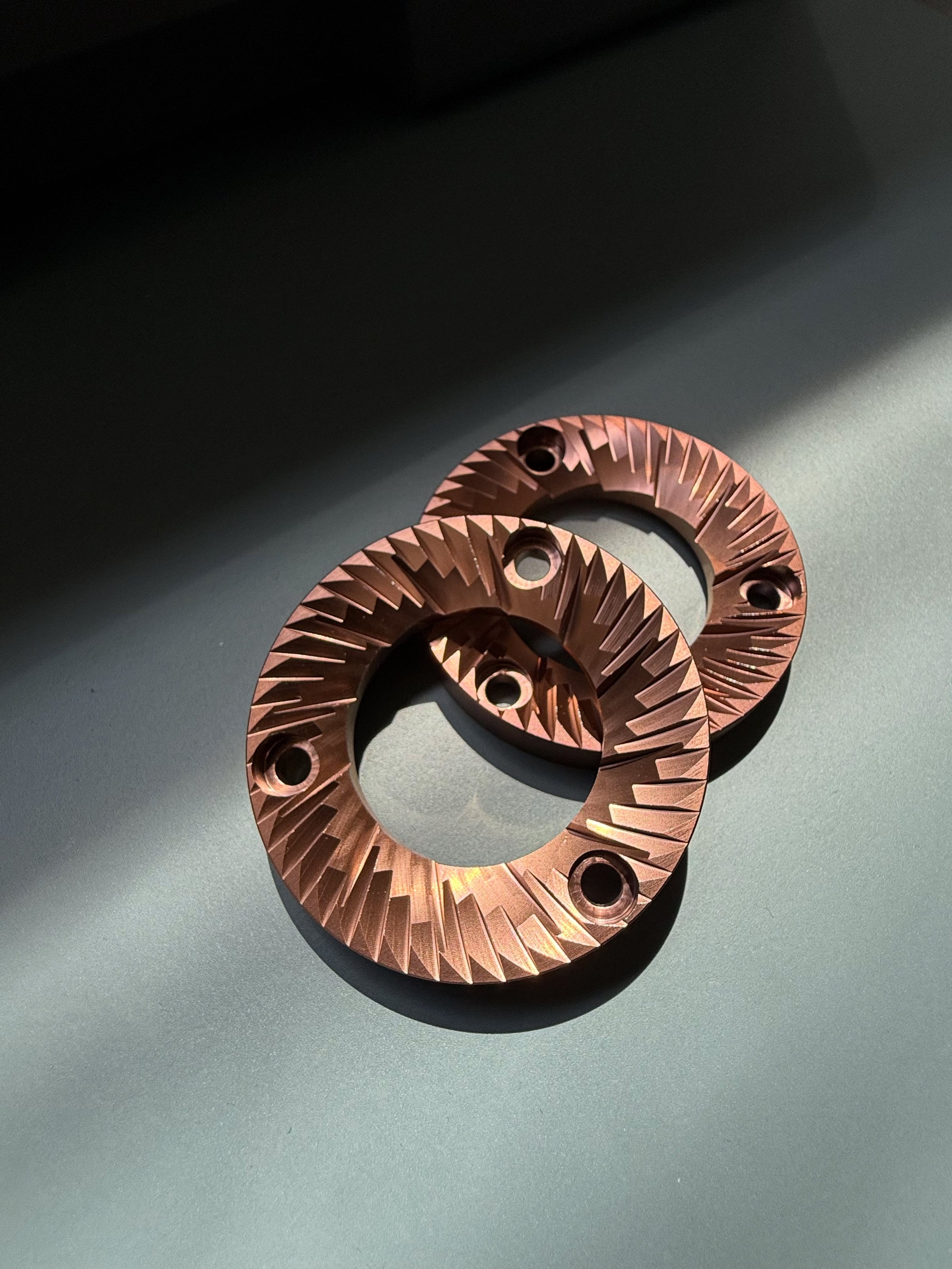 Red titanium Burrs placed on top of each other against a wooden background 