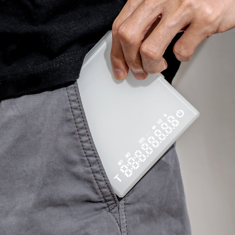 White Grind Logic Mini Espresso Scale being carried in a pocket, showing its compact portable size